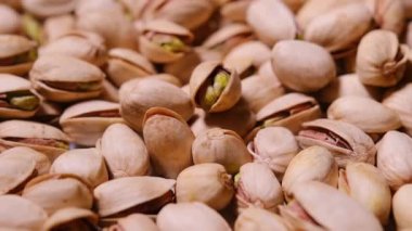 Kabuklarında kavrulmuş ve tuzlanmış şam fıstıklarının üst üste yığıldığı aşırı yakın plan.
