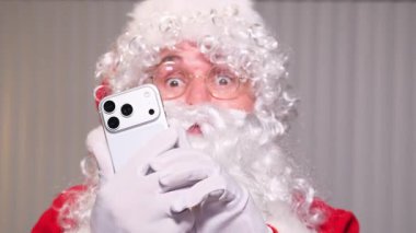 Şok olmuş bir ifadeyle komik Noel Baba selfie çekiyor ya da Noel için video blogu kaydediyor.