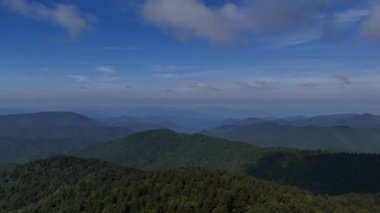 Yeşil orman tepelerinde hareket eden bulutlu ve gölgeli güneşli dağ manzarası