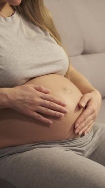 Evdeki kanepede oturan ve hafifçe karnına dokunan bir kadın görmeyi bekliyorum..