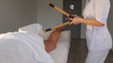 Kadın müşteri, spa 'da bacaklarına rahatlatıcı ve tedavi edici bir bambu masajı yaptırıyor.