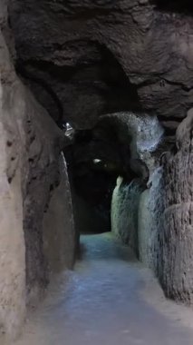 Kaya duvarları olan karanlık ve dar bir mağara koridorunda ileri doğru yürüme hareketi.