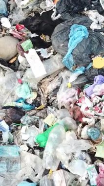 Plastik torbalar, şişeler ve diğer biyolojik olarak çözülemeyen atıklarla dolu büyük bir çöp yığınının tepeden tırnağa görüntüsü