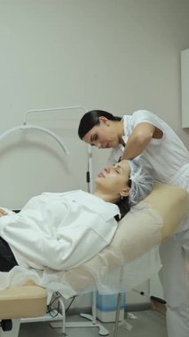 Profesyonel güzellik uzmanı güzellik kliniğinde bir kadının yüzüne kozmetik ürün uyguluyor.