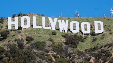Los Angeles, Kaliforniya 'da açık mavi gökyüzü olan yeşil bir tepede duran ikonik Hollywood tabelası.