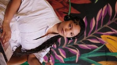 Genç Afro-Amerikalı kadın evden bilgisayarını kullanarak kulaklıkla müzik dinliyor.