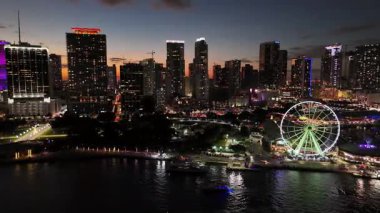 Miami şehir merkezinin panoramik hava manzarası ve alacakaranlıkta yanan dönme dolap.