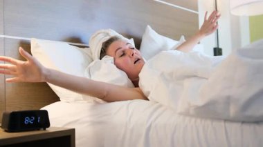 Uykulu genç bir kadın sabah duştan sonra uyanıyor, esniyor ve esniyor.