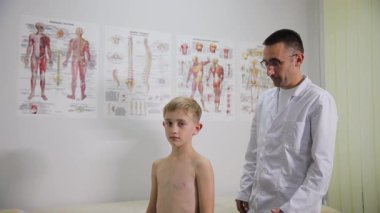 Genç bir hasta, tıbbi muayenehanede erkek bir kayropraktik uzmanı tarafından muayene ediliyor.