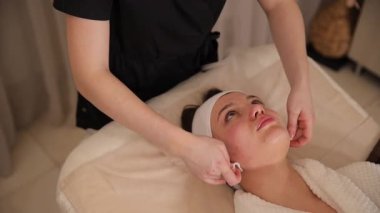 Estetisyen, cilt bakımı sırasında hastaların yüzünü pamukla nazikçe temizler.