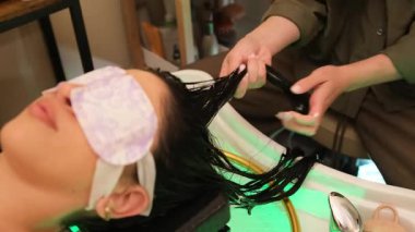 Rahat bir kadın, profesyonel güzellik merkezinde saç maskesi ve kafa masajı yaptırıyor.