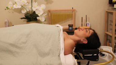 Kafası lavaboda uzanmış, kaplıcada rahatlatıcı saç yıkama tedavisi gören bir kadın.