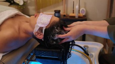 Güzellik salonunda ya da kaplıcada saç yıkayan ve kafa masajı yapan bir kadın.