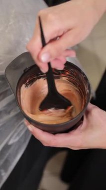 Profesyonel kuaför bir güzellik salonunda saç kremi hazırlıyor ve karıştırıyor.