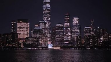 Manhattan finans bölgesinin parlak gökdelenleri geceleyin Hudson Nehri 'ni yansıtıyor.