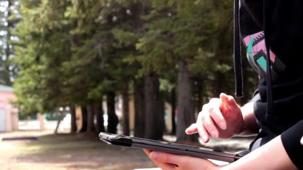 Closeup ενός κοριτσιού χρησιμοποιώντας tablet στο πάρκο — Αρχείο Βίντεο