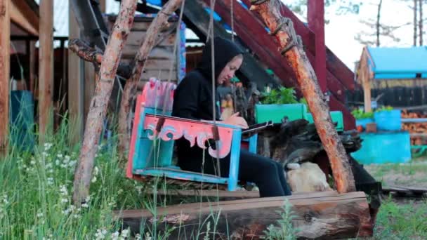 Девушка с табличкой на деревянном качеле — стоковое видео