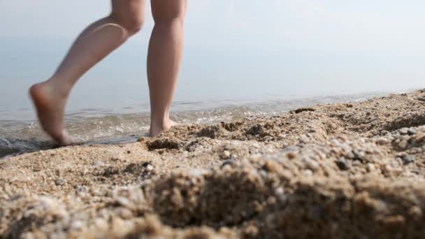 Weibliche Beine und Füße beim Spazierengehen am Sandstrand. Zeitlupe — Stockvideo
