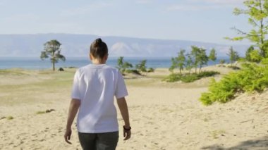 Kız güneşli bir günde kumsal boyunca yürür.