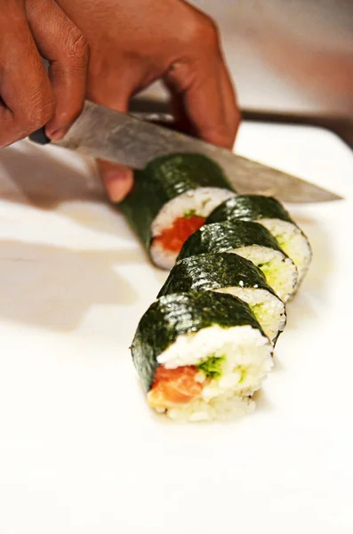 Şef suşi roll beyaz tahta üzerinde keser