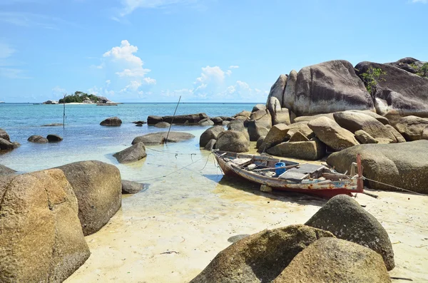 Una spiaggia con formazioni di pietra granitica sparsi intorno e barca in legno distrutto — Foto Stock