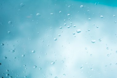 Su arka plan damla. Su cam pencere üzerinde üzerinde mavi gökyüzü düşüyor..