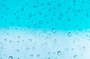 Su arka plan damla. Su cam pencere üzerinde üzerinde mavi gökyüzü düşüyor.