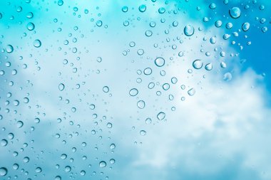 Su arka plan damla. Su cam pencere üzerinde üzerinde mavi gökyüzü düşüyor.