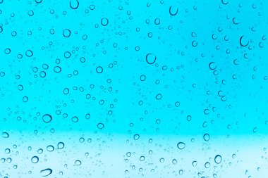 Su arka plan damla. Su cam pencere üzerinde üzerinde mavi gökyüzü düşüyor.