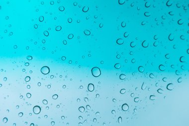 Su arka plan damla. Su cam pencere üzerinde üzerinde mavi gökyüzü düşüyor.