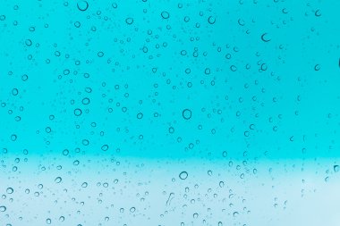 Su arka plan damla. Su cam pencere üzerinde üzerinde mavi gökyüzü düşüyor.