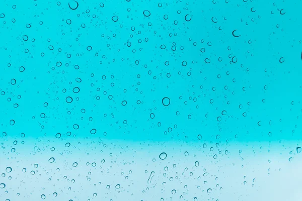 Su arka plan damla. Su cam pencere üzerinde üzerinde mavi gökyüzü düşüyor.