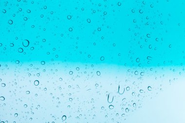 Su arka plan damla. Su cam pencere üzerinde üzerinde mavi gökyüzü düşüyor.