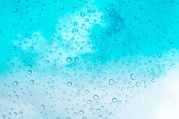 Su arka plan damla. Su cam pencere üzerinde üzerinde mavi gökyüzü düşüyor.