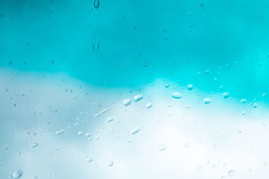 Su arka plan damla. Su cam pencere üzerinde üzerinde mavi gökyüzü düşüyor..