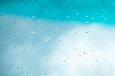 Su arka plan damla. Su cam pencere üzerinde üzerinde mavi gökyüzü düşüyor..