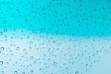 Su arka plan damla. Su cam pencere üzerinde üzerinde mavi gökyüzü düşüyor.