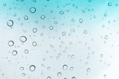 Su arka plan damla. Su cam pencere üzerinde üzerinde mavi gökyüzü düşüyor.