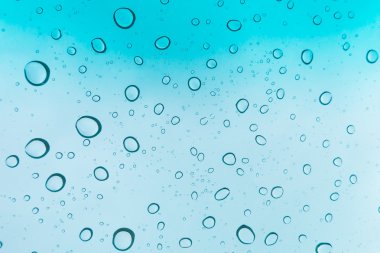 Su arka plan damla. Su cam pencere üzerinde üzerinde mavi gökyüzü düşüyor.