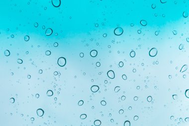 Su arka plan damla. Su cam pencere üzerinde üzerinde mavi gökyüzü düşüyor.