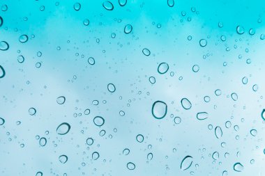 Su arka plan damla. Su cam pencere üzerinde üzerinde mavi gökyüzü düşüyor.