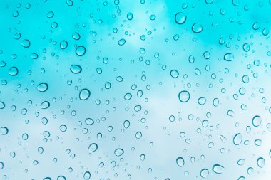 Su arka plan damla. Su cam pencere üzerinde üzerinde mavi gökyüzü düşüyor.