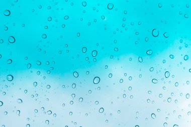 Su arka plan damla. Su cam pencere üzerinde üzerinde mavi gökyüzü düşüyor.