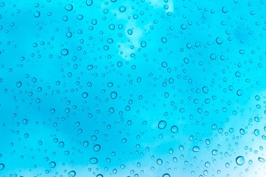 Su arka plan damla. Su cam pencere üzerinde üzerinde mavi gökyüzü düşüyor.