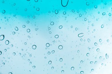 Su arka plan damla. Su cam pencere üzerinde üzerinde mavi gökyüzü düşüyor.