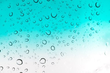 Su arka plan damla. Su cam pencere üzerinde üzerinde mavi gökyüzü düşüyor..