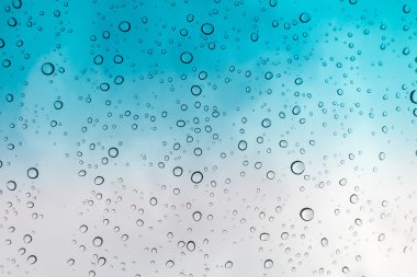 Su arka plan damla. Su cam pencere üzerinde üzerinde mavi gökyüzü düşüyor..