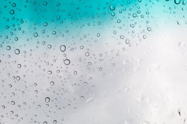 Su arka plan damla. Su cam pencere üzerinde üzerinde mavi gökyüzü düşüyor..