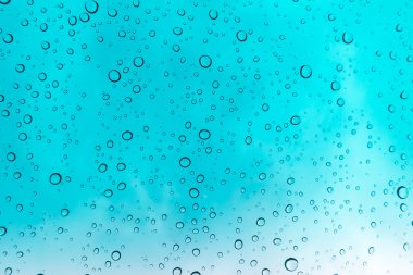 Su arka plan damla. Su cam pencere üzerinde üzerinde mavi gökyüzü düşüyor..