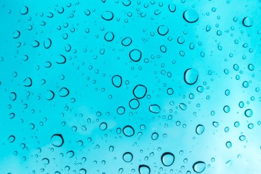 Su arka plan damla. Su cam pencere üzerinde üzerinde mavi gökyüzü düşüyor..